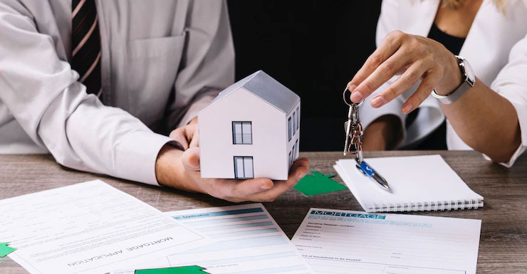 Realtor handing the keys to house to a person holding a small model house in their hands